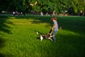 The naughty boy plays with doggy on a green glade in park.