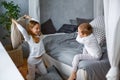 Naughty children a little boy and a girl in pajamas fought with pillows on the bed in a gray bedroom. They like this game. Pillow Royalty Free Stock Photo