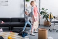 naughty daughter holding cardigan of tired mother cleaning