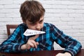 Naughty disobedient schoolboy making paper plane of his home tas Royalty Free Stock Photo