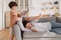 Naughty small kid rumbling kitchenware as stressed and tired mother sleeping on sofa in living room Royalty Free Stock Photo