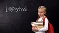 Naughty schoolgirl with books standing near blackboard, I love school phrase