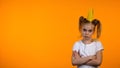 Naughty schoolgirl in paper crown and hands crossed on chest looking to cam Royalty Free Stock Photo