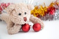 A naughty teddy bear plays a red ball decorate Christmas tree