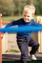 A naughty, very agile boy actively runs through the labyrinths of an outdoor playground