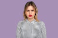 Naughty woman in bad mood. Beautiful blond woman with bright red lips in striped blouse frowning face looking displeased