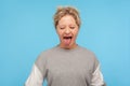 Naughty woman with short hair in sweatshirt standing with closed eyes and sticking out tongue Royalty Free Stock Photo