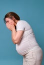 Nausea in pregnant woman, studio shot on blue background