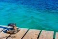 Nautical bollard at wooden pier at harbor with calm sea waves