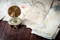 Nautical compass in front of fake pirates treasure map on wooden table