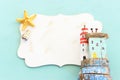 nautical concept with house and lighthouse driftwood, seashells, star fish, blank board for copy space over mint blue wooden Royalty Free Stock Photo