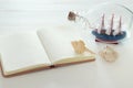 nautical concept image with sail boat in the bottle and empty open notebook over white wooden table. Royalty Free Stock Photo