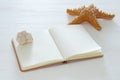 nautical concept image with starfish and empty open notebook over white wooden table. Royalty Free Stock Photo