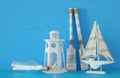 nautical concept with white decorative lighthouse lantern, wooden oars, letter in the boat and boat over blue background.