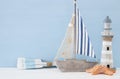 nautical concept with white decorative lighthouse, wooden oars and boat over blue background.