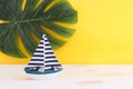 nautical concept with white decorative sail boat, seashells over wooden table and yellow background Royalty Free Stock Photo