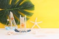 nautical concept with white decorative sail boat, seashells over wooden table and yellow background Royalty Free Stock Photo