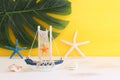 nautical concept with white decorative sail boat, seashells over wooden table and yellow background Royalty Free Stock Photo