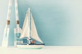 nautical concept with white decorative sail boat and wooden oars over blue background. Royalty Free Stock Photo