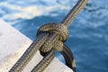 Nautical knot on a yacht rope against the background of water on the pier. Yacht tied with a rope in the seaport. Royalty Free Stock Photo