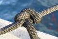 Nautical knot on a yacht rope against the background of water on the pier. Yacht tied with a rope in the seaport. Royalty Free Stock Photo