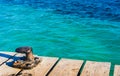 Nautical maritime scene with bollard on wooden jetty and blue turquoise sea water