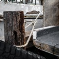 A nautical rope, tied with a knot to a wooden piling to moor a fishing boat Royalty Free Stock Photo