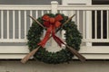 Nautical wreath with old worn oars and sparkly red bow mounted on wooden porch - closeup
