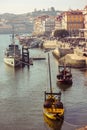 Naval ship and traditional wooden rabelo boats with wine barrels on the Douro river in Porto, Portugal