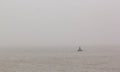 Navigational buoy and seagull in the sea on the morning mist