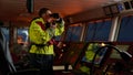 Navigator. pilot, captain as part of ship crew performing daily duties with VHF radio, binoculars on board of modern ship with