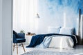 Navy blue armchair and king size bed with blankets and pillows i Royalty Free Stock Photo