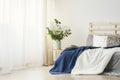 Navy blue blanket thrown on double bed with lights on bedhead st Royalty Free Stock Photo