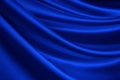 Navy blue silk satin. Soft, wavy folds. Shiny fabric surface. Luxury background with copy space for design.