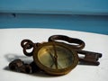 Navy compass and three solid iron, rusted keys on white and blue background.