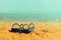 Navy flip flop on yellow sand beach with blue sea and sky background. Copy space. Summer, holiday and travel concept Royalty Free Stock Photo