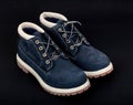 Navy lady's boots with shoelace and sole on black background.