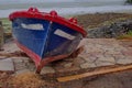 A navy and red wood fishing boat stranded on the shore of an estuary