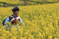 NaXi woman dressed with traditional minority attire in a rapeseed flower near ShiGu village on the first bend of the Yangtze River