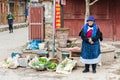 Naxi woman selling vegetables in the streets of Baisha village Yunnan China