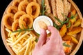 Beer plate fried ribs onion rings french fries fish nuggets on a wooden plate on a black background4