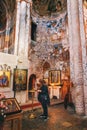 Nikortsminda, Georgia - 28 April, 2017: Woman prays in Interior and frescoes mural in Nikortsminda Cathedral in Racha, Georgia