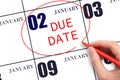 Hand writing text DUE DATE on calendar date January 2 and circling it. Payment due date Royalty Free Stock Photo