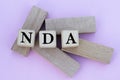 NDA - acronym on wooden cubes against the background of wooden bars Royalty Free Stock Photo