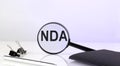 NDA text concept. Magnifier glass with text with notebook and pen Royalty Free Stock Photo