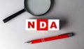 NDA word on wooden cubes with pen and magnifier Royalty Free Stock Photo