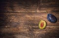 ÃÅ¾ne single plum and a half of plum with stone over dark wooden board. Fruit background. Text space. Top view.