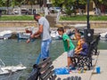 Nea Artaki, Evia island, Greece. July 2019: Fisherman with children fishing on the waterfront on a sunny afternoon on the calm Aeg