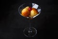 Neapolitan Rum baba or baba au rum in a martini glass with a cocktail cherry on a black background. Small yeast cakes soaked in