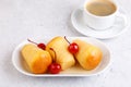 Neapolitan Rum baba (or baba au rum) on a white plate with a cocktail cherry and a cup of coffee. Small yeast cakes.